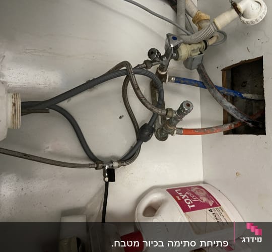 צינורות מים מתחת לכיור עם חיבורים וברזים